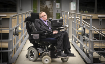 Immagine che ritrae Stephen Hawking sulla sua sedia a rotelle con sintetizzatore vocale